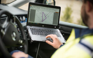Fälttekniker tittar i laptop i en bil. Skärmen i laptopen visar en ritning med en lila markering.